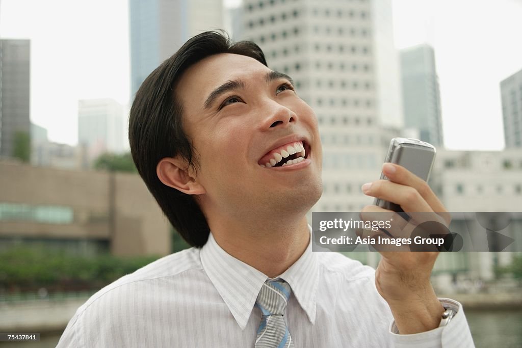 Businessman holding mobile phone, buildings in the background