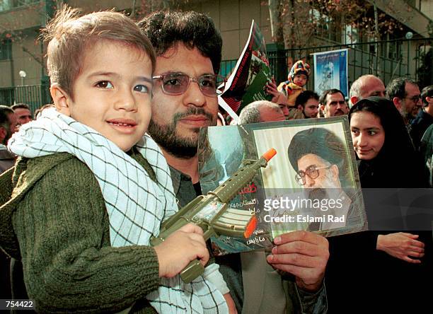 Child holds a toy gun as his father carries him during a rally in support of the Palestinian Intifada against Israel December 14, 2001 in Tehran,...