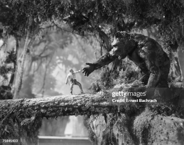 Man meets giant ape across a fallen tree branch in a scene from the classic monster movie 'King Kong', 1933.