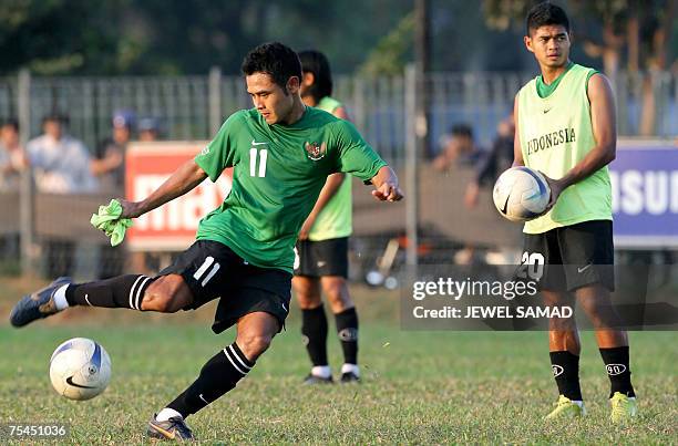 Jakarta, Java, INDONESIA: Indonesian national football team captain Ponaryo Astaman kicks a ball as his teammate Bambang Pamungkas looks on during a...