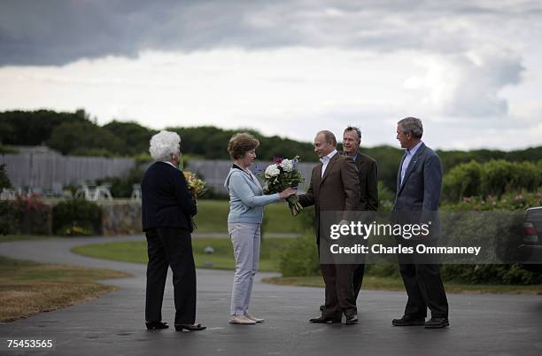 First Lady Laura Bush receives flowers from Russian President Vladamir Putin as he arrives to meet with US President George W. Bush at Walker's on...