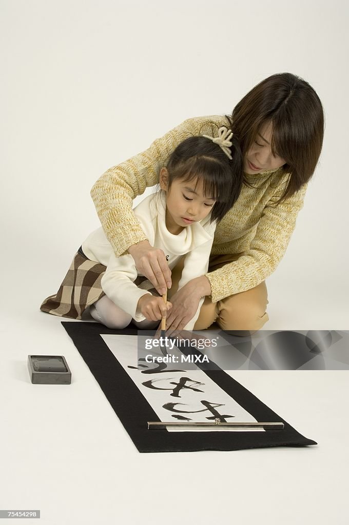 Mother and daughter writing letters with ink brush