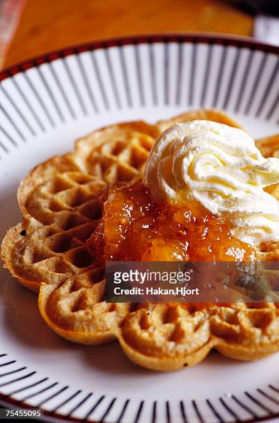 a waffle with jam and whipped cream on a plate close-up. - waffles stock pictures, royalty-free photos & images