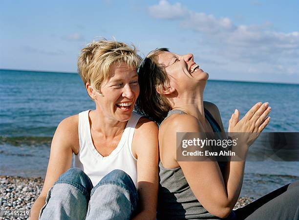 two laughing women on a beach. - female 40 year old beach stock pictures, royalty-free photos & images
