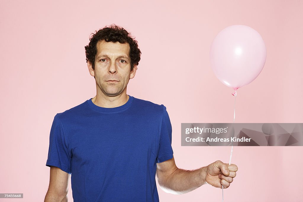 A middle-aged man holding a pink balloon.