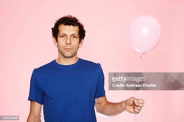 a middle-aged man holding a pink balloon. - blue tshirt stock pictures, royalty-free photos & images