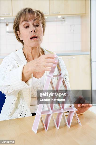 woman building a house of cards. - house of cards stock pictures, royalty-free photos & images