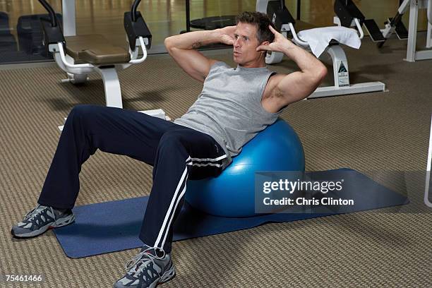 mature men doing exercise on fitness ball in gym - スウェットパンツ ストックフォトと画像