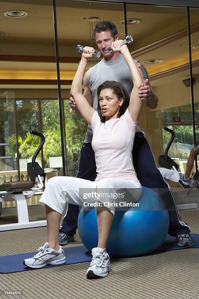 Male instructor helping woman in gym