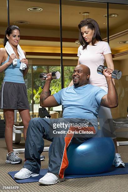 woman giving weight training to man with dumbbells, smiling - musculation des biceps photos et images de collection