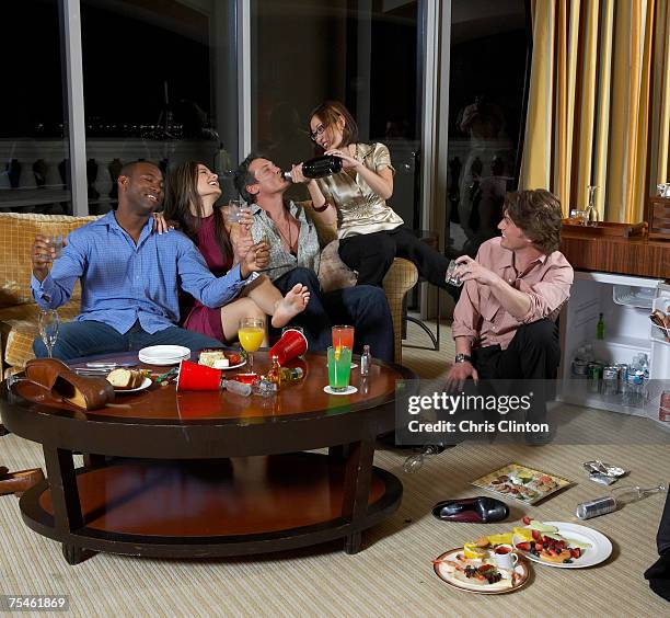 group of people celebrating in hotel room, woman pouring wine in to man's mouth - mini bar imagens e fotografias de stock