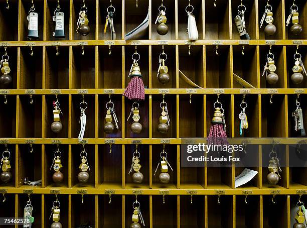 hotel room keys in pigeon holes behind reception desk - hotel key stock-fotos und bilder