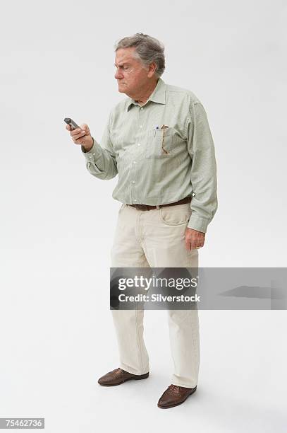 senior man looking at mobile phone - grumpy old man stock pictures, royalty-free photos & images