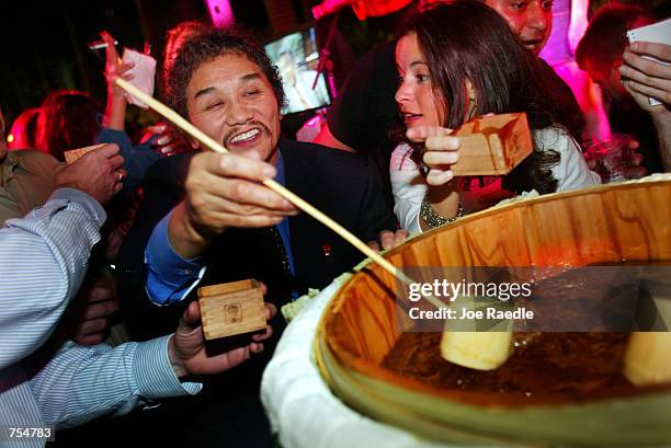 Rocky Oaki, the founder of the Benihana corp., uses a dipper to pour sake for guests January 23, 2002 at the debut of the Sushi Doraku restaurant...