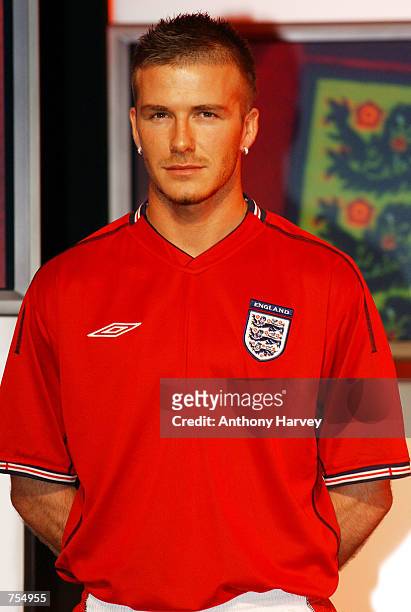 England soccer team captain David Beckham models the new England away strip--a red short-sleeved shirt, white shorts and red socks--February 11, 2002...