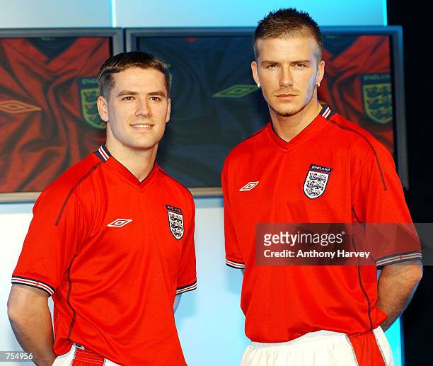 England soccer team captain David Beckham and teammate Michael Owen model the new England away strip--a red short-sleeved shirt, white shorts and red...