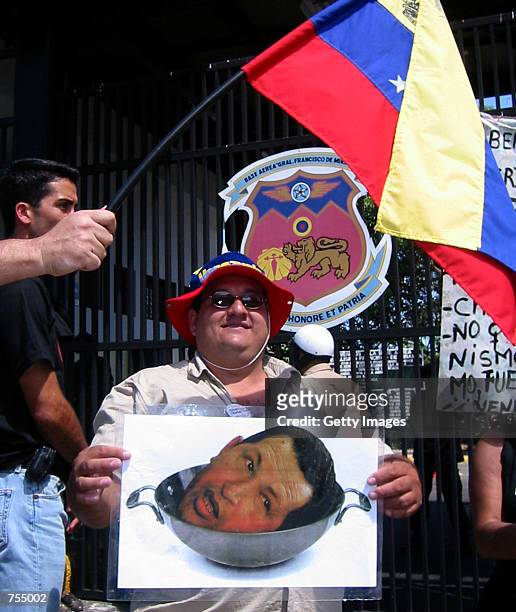 Supporter of Venezuelan Air Force Colonel Pedro Soto holds a poster of President Hugo Chavez's head in a pot in front of La Carlota military airport...