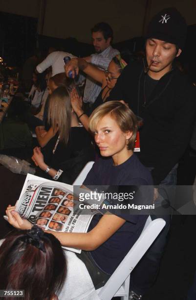 Model Brigitte Hall reads the New York Post as her is styled for the Luca Luca Fashion Show February 12, 2002 in New York City.