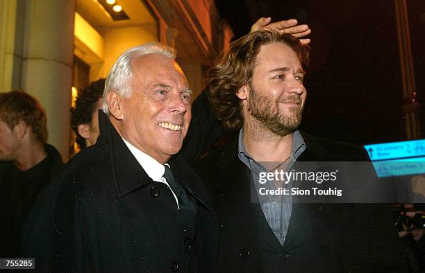 Fashion designer Giorgio Armani shelters actor Russell Crowe from the rain February 19, 2002 as they leave a launch party for the new Emporio Armani...
