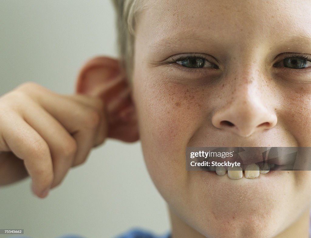 Boy (10-11) pulling ear,portrait,close-up