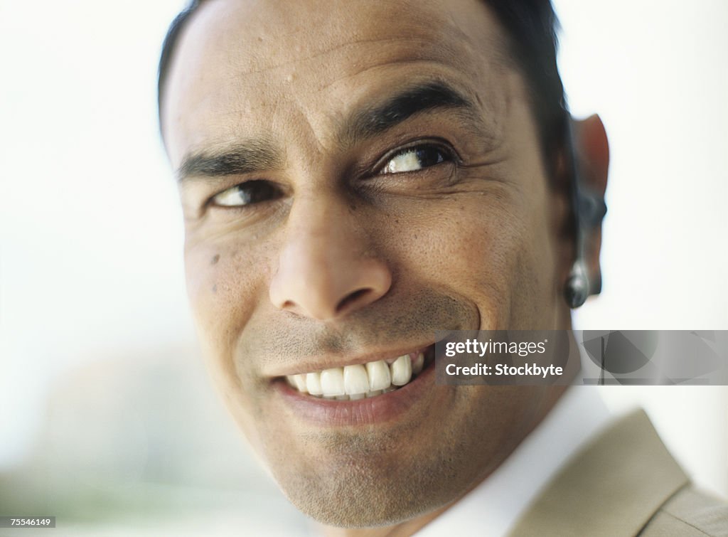 Business man wearing hands free device,smiling,close up