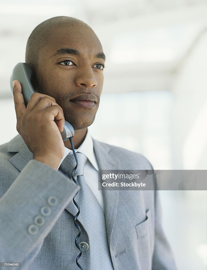 Mid adult businessman using phone,looking away,upper half