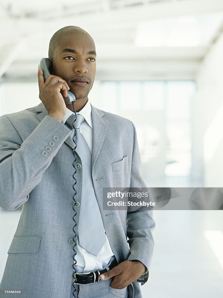 Mid adult businessman using phone,looking away,waist up