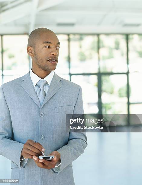 mid adult businessman using palmtop indoors,looking away,upper half - half shaved hair stockfoto's en -beelden