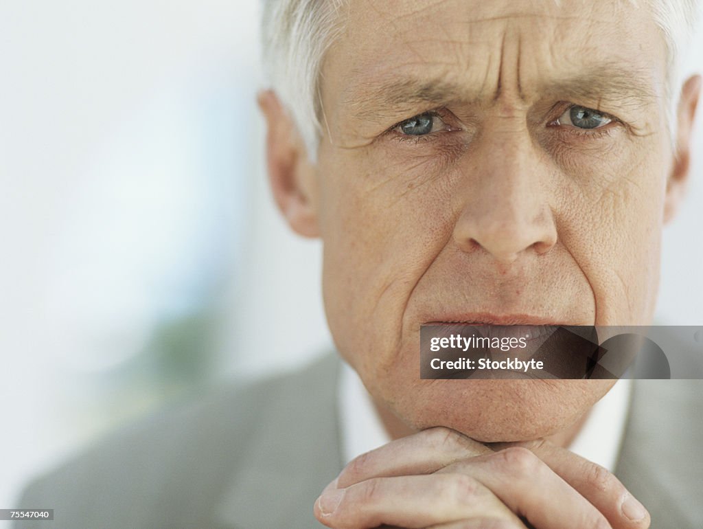 Senior businessman with hands clasped on chin,portrait,close-up