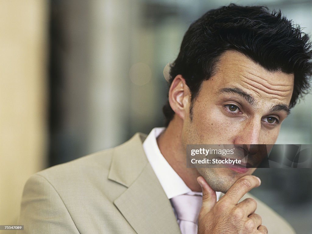 Business man with hand on chin,looking away,close-up