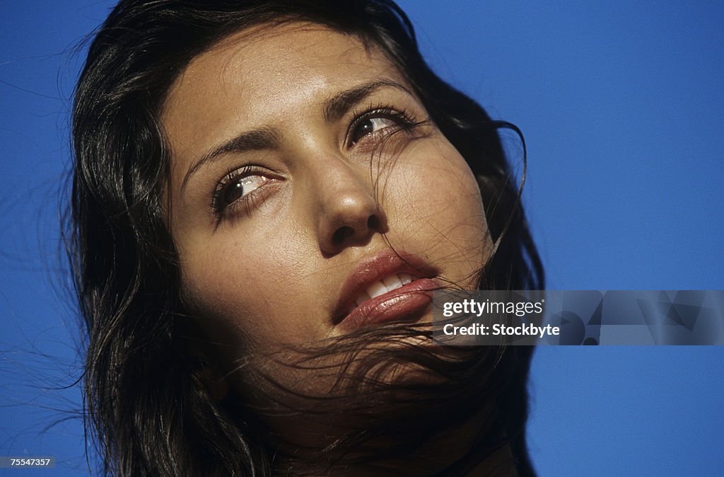 Young woman against clear sky,looking away,close-up of face