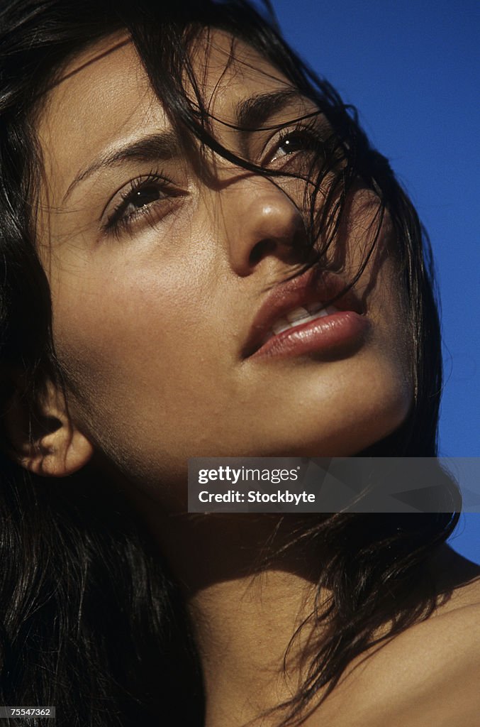Young woman against clear sky,looking away,close-up