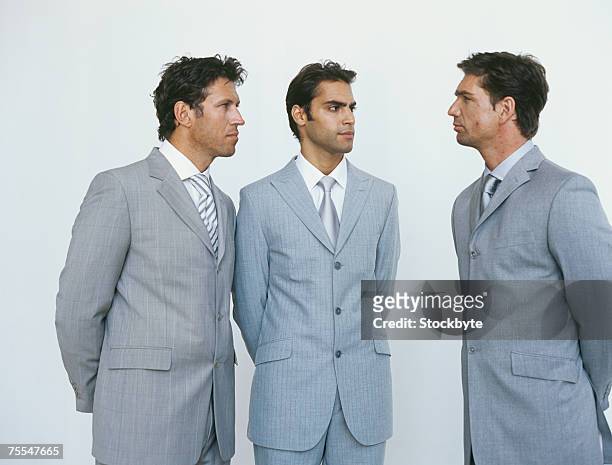 three business men in suits looking at each other,three quarter length - three quarter length stock-fotos und bilder