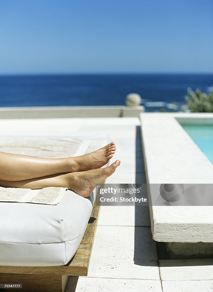 Woman lying by swimming pool,low section