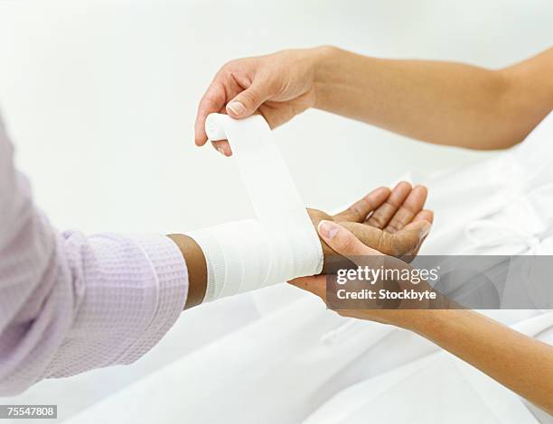 nurse wrapping bandage around patient's wrist,close-up on hands - wrapping arm stock pictures, royalty-free photos & images