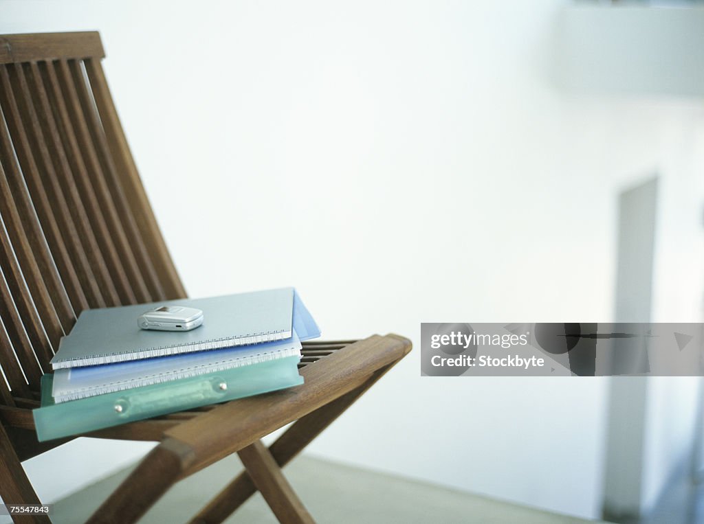 Notebooks and mobile phone on chair,indoors