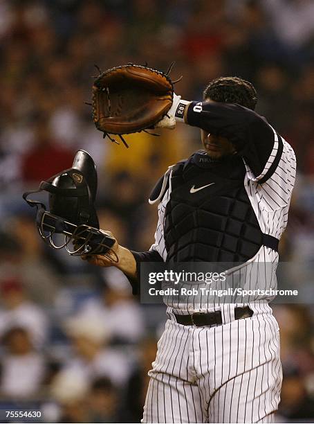 Jorge Posada of the New York Yankees wipes his face with his glove during a game against the Boston Red Sox on April 27, 2006 in the Bronx borough of...