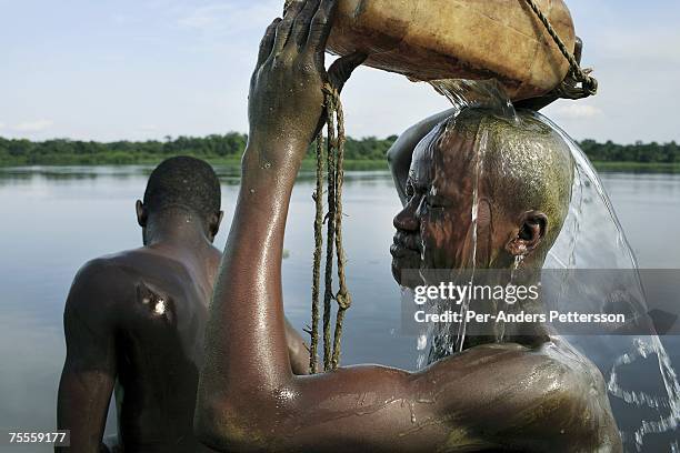 Ngisa Dieu, age 17 , a crew member, tries to wash off palm oil from his body, on a boat with destination Kinshasa on April 7, 2006 in Bumba, Congo,...