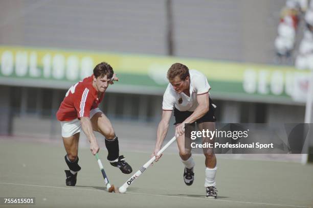 English field hockey player Sean Kerly of the Great Britain team pictured left in action fighting with a West Germany player for the ball during play...