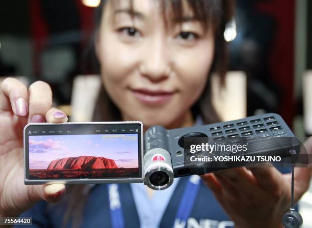 Japan's electronics giant NEC employee Yoshie Takagi dislays the prototype model of multi-media mobile phone, eauipped with a high-spec video...