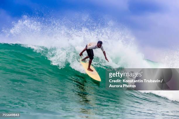 side view of surfer riding splashing wave, kuta, lombok, indonesia - kuta stock-fotos und bilder