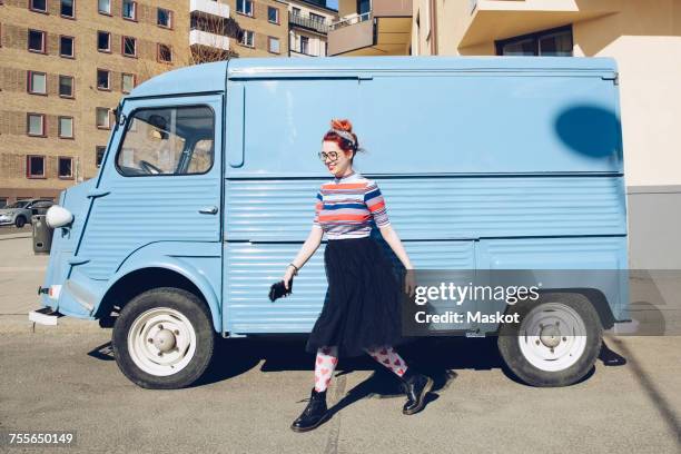 young woman walking by blue mini van on city street - car scandinavia stock pictures, royalty-free photos & images