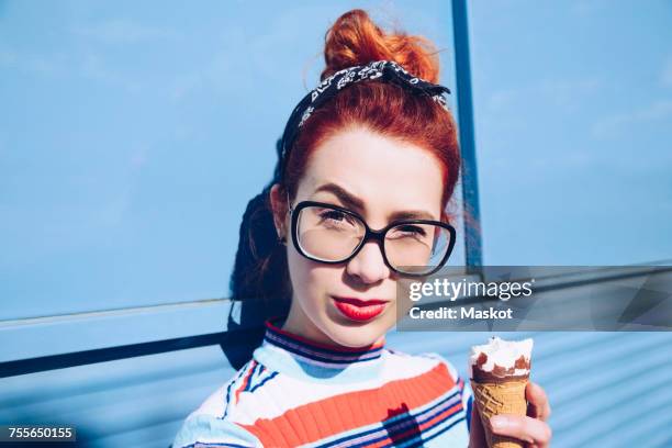 portrait of redhead young woman holding ice cream cone against mini van - cool cars stockfoto's en -beelden