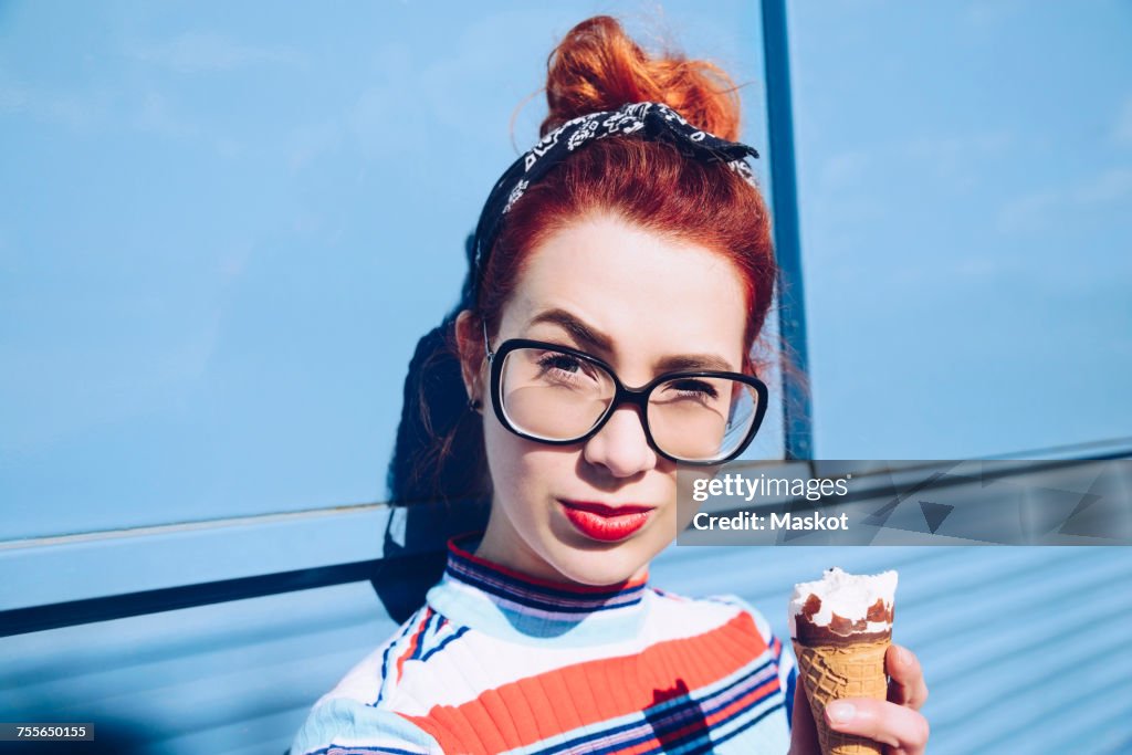 Portrait of redhead young woman holding ice cream cone against mini van