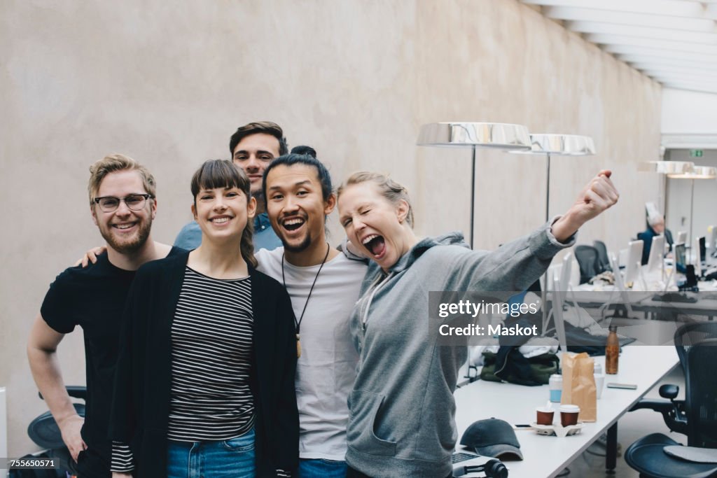 Excited female computer programmer screaming while standing with colleagues in office