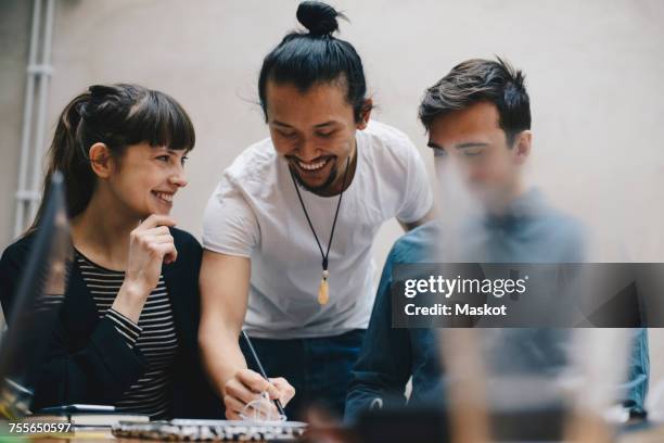 happy computer programmer writing while discussing with colleagues in office - programmer team stock pictures, royalty-free photos & images