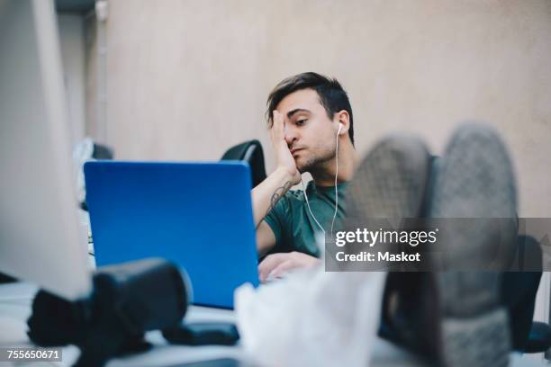 tired computer programmer using laptop while sitting with feet up at desk in office - programmer working stock pictures, royalty-free photos & images