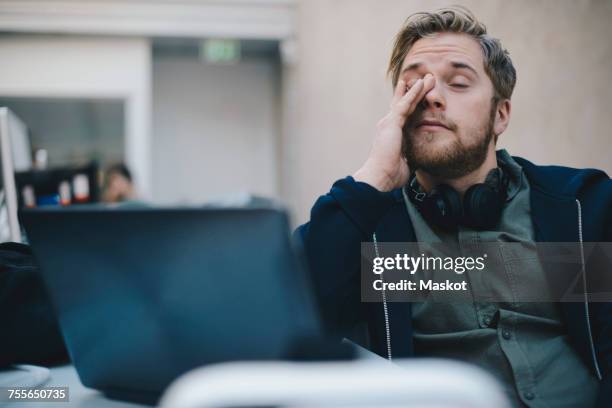 tired computer programmer rubbing eyes while sitting in office - hipster icon stock pictures, royalty-free photos & images