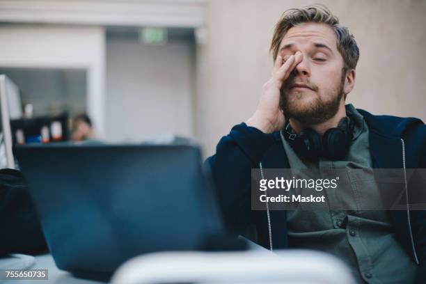 tired computer programmer rubbing eyes while sitting in office - tired bildbanksfoton och bilder