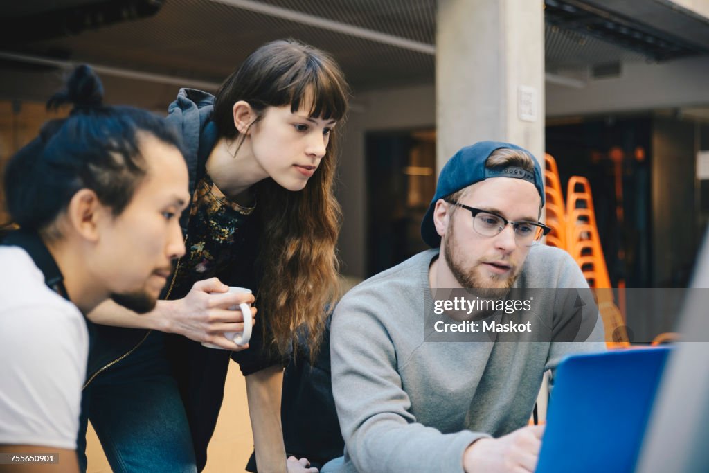 Male and female computer programmers using laptop at desk in office